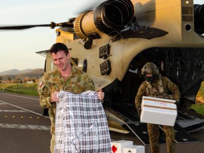 Army personnel unloading supplies from helicopter