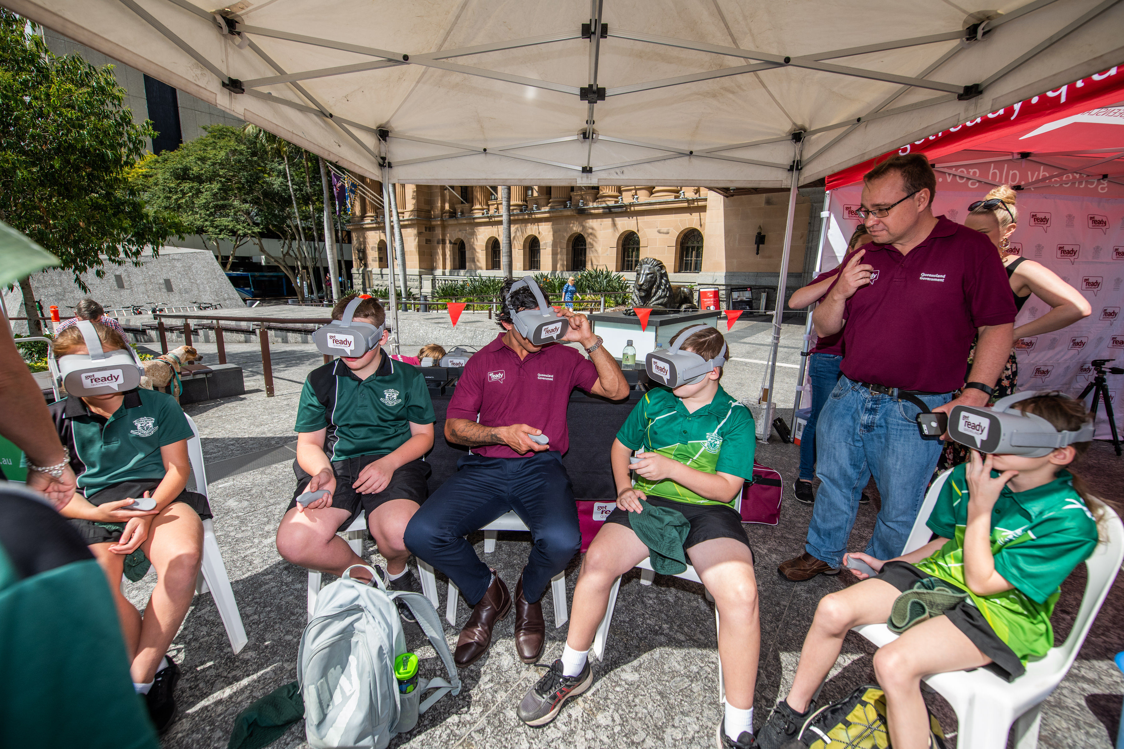 Get Ready Queensland ambassador Johnathan Thurston and students having a go at the preparedness virtual reality game