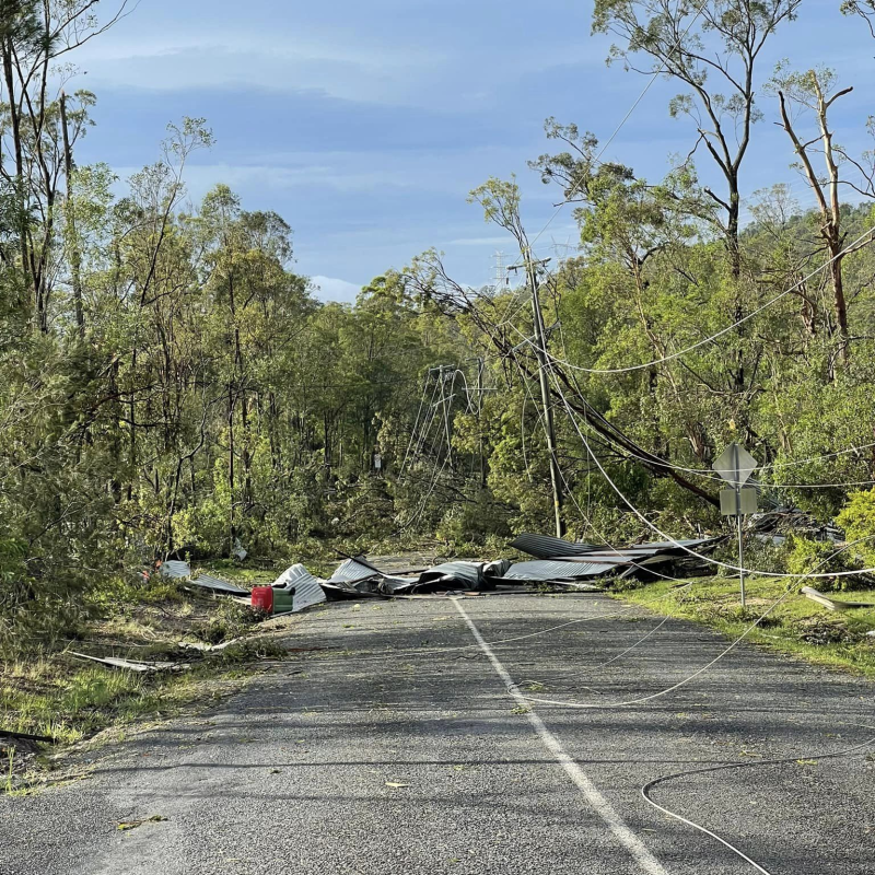 Powerlines and a shed are strewn across a road following destructive storms in the Scenic Rim, December 2023.