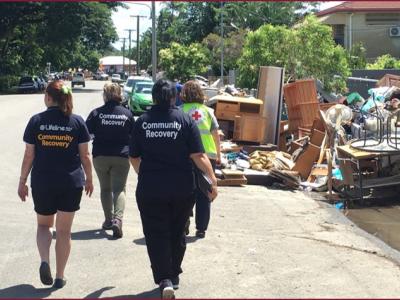 Community recovery workers walking down street with flood debris