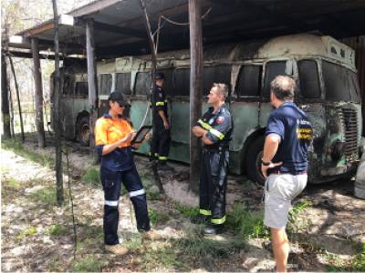 Workers standing in front of burnt out bus