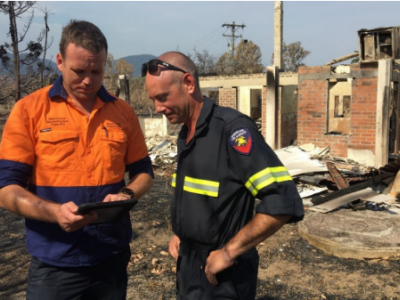 Workers undertaking damage assessments near burnt out building