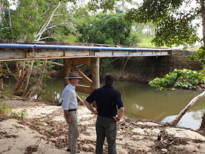 Two people viewing damage next to bridge