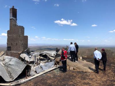 People standing next to destroyed building