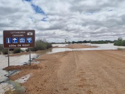 Tourist sign and road flooding at Cuttaburra Crossing, Diamantina